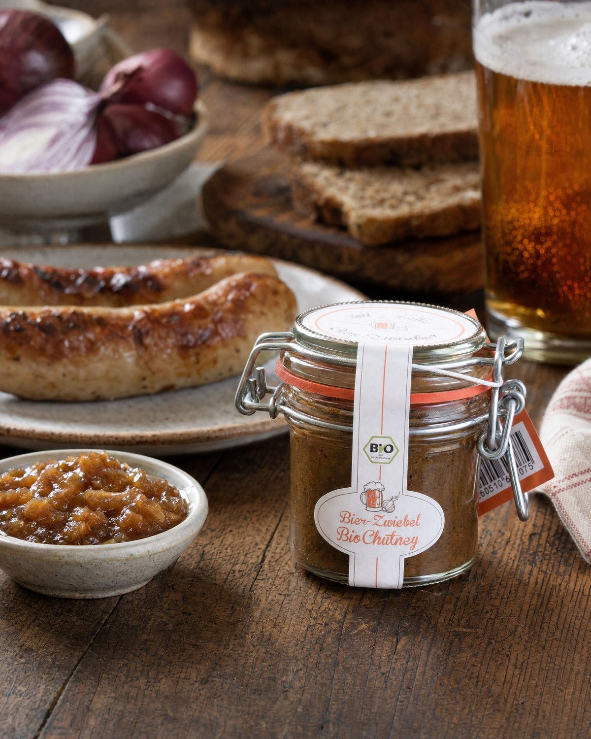 sell g'machts Bier-Zwiebel Bio-Chutney zur Brotzeit mit Bratwurst, Roggenbrot, roten Zwiebeln und einem Glas Bier